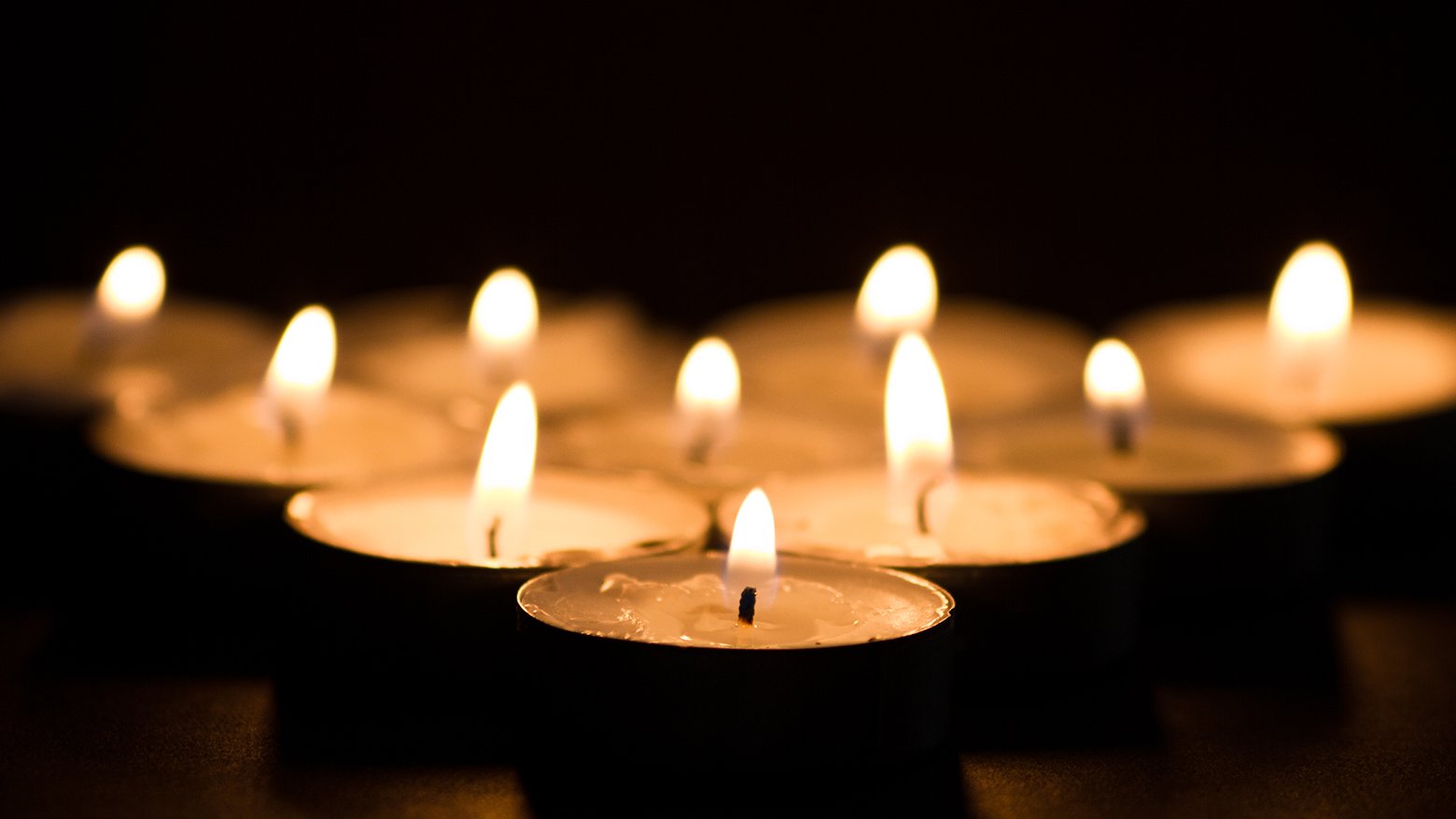 Several lit candles burn on a table