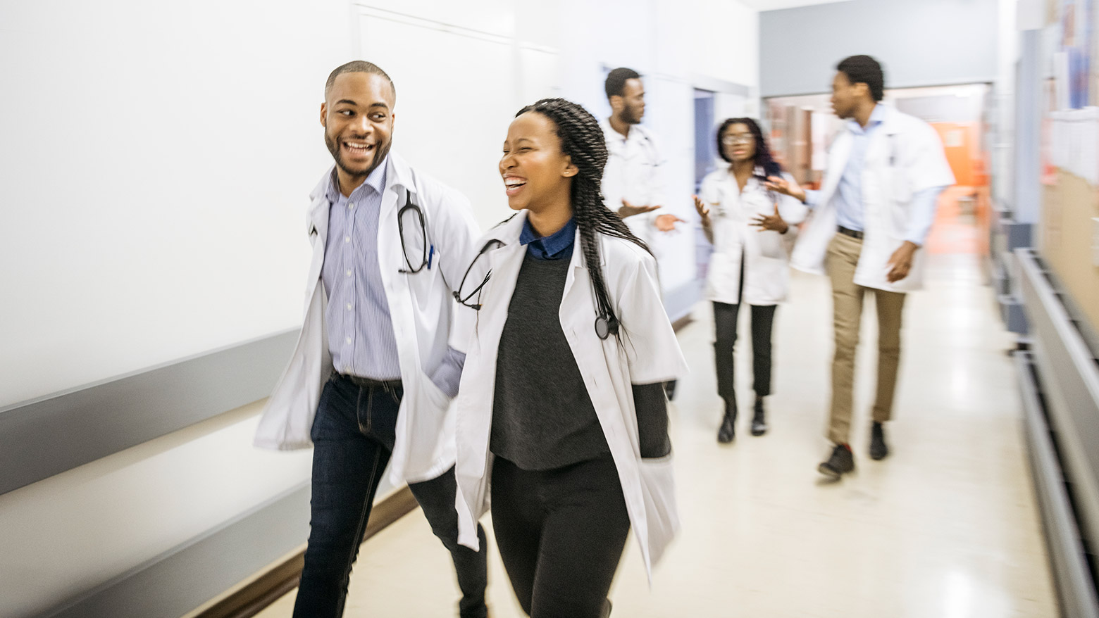 A group of doctors converse while walking down a hospital hallway