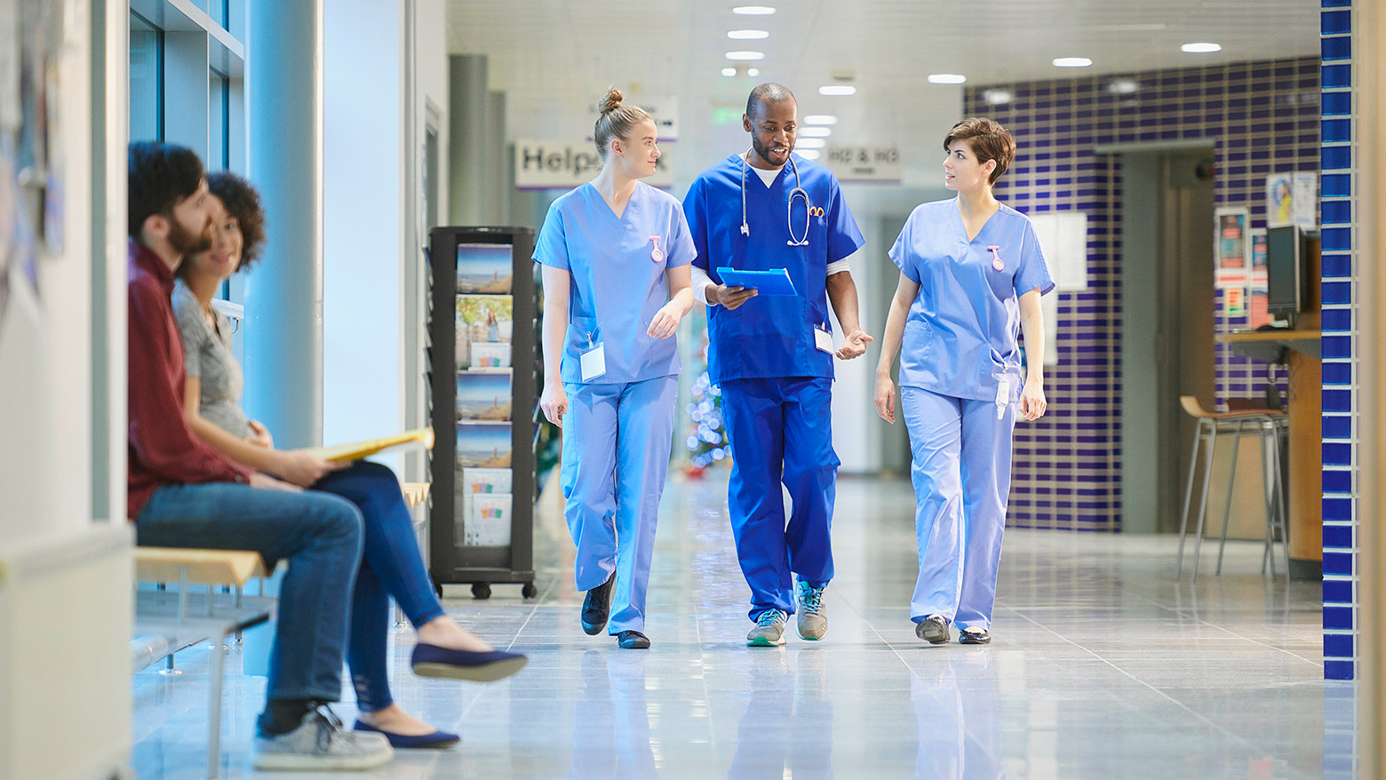 A trio of doctors discuss while walking down a hospital hallway