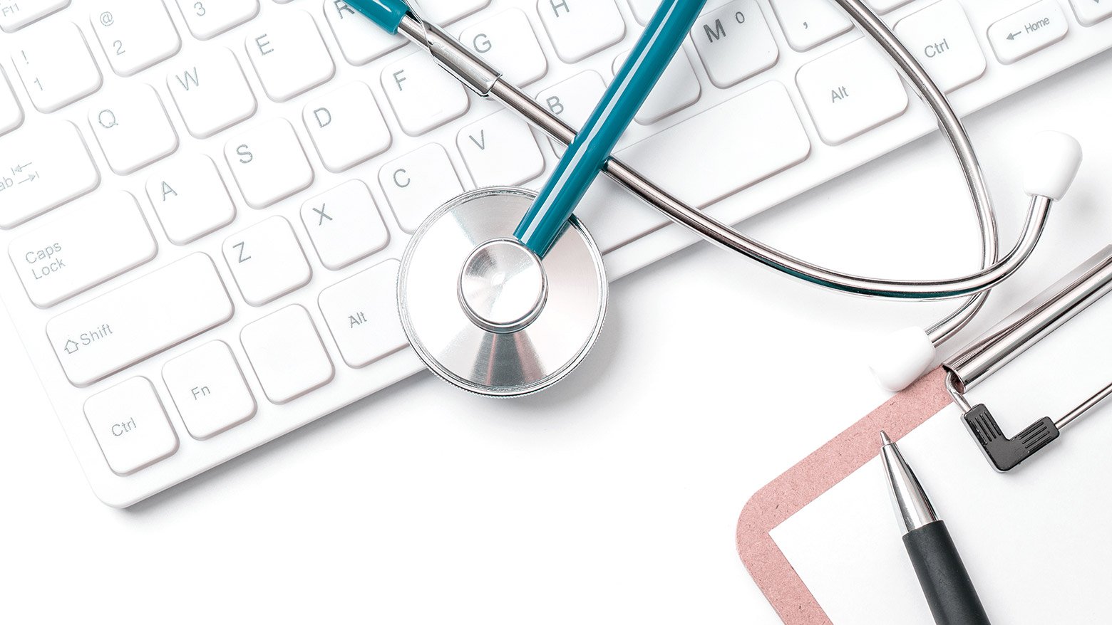 A stethoscope on top of a keyboard and a pen on top of a clipboard
