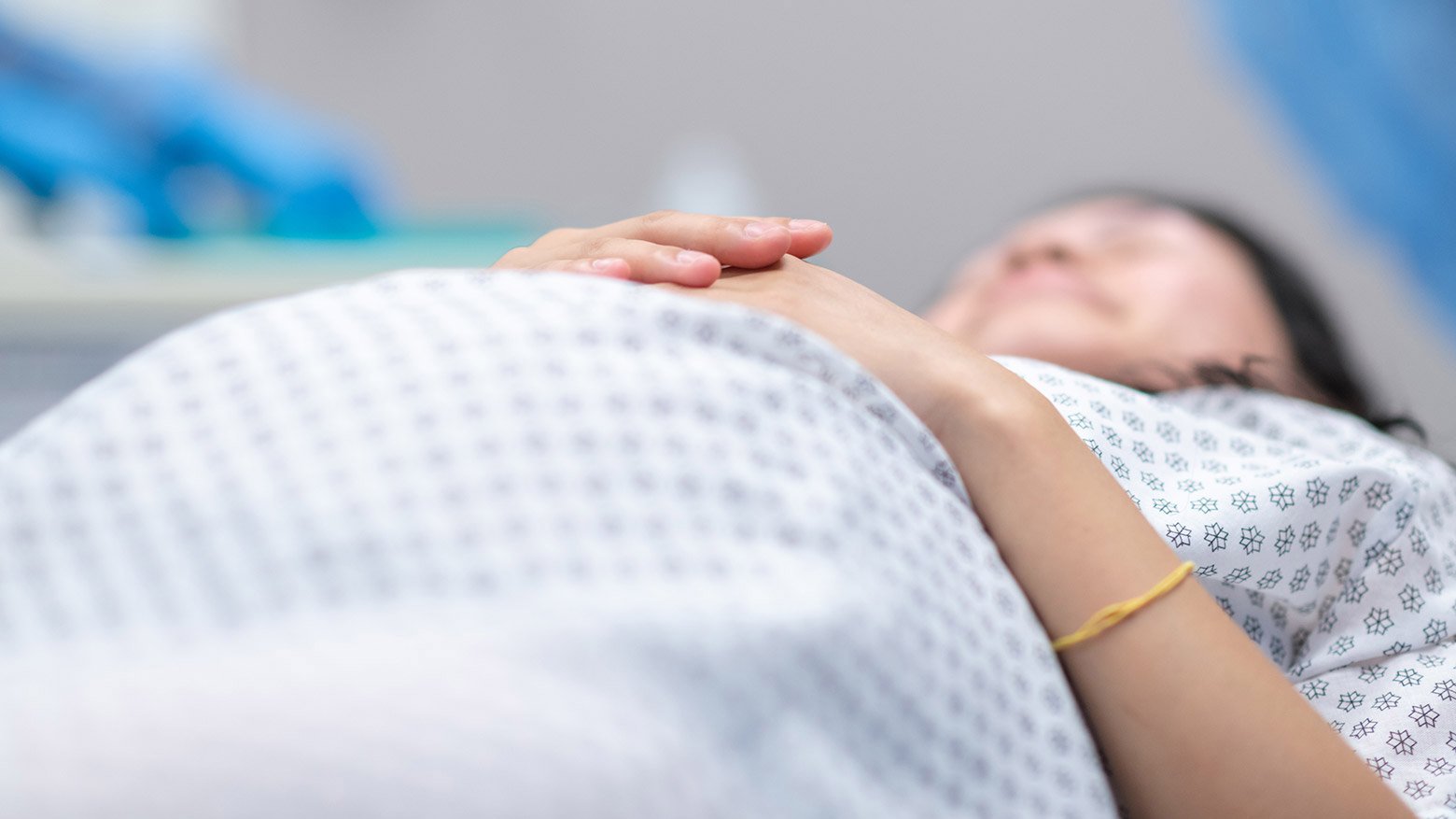 A pregnant patient in a hospital gown is lying down