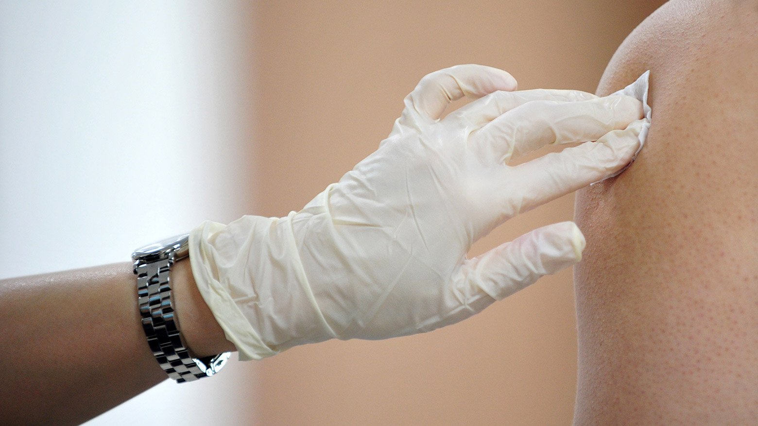 A health-care worker pressing a gauze on a patient's arm after receiving a needle.