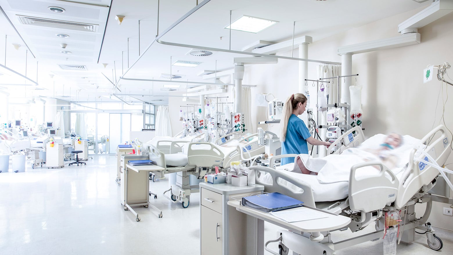 A doctor tends to a patient in a hospital bed
