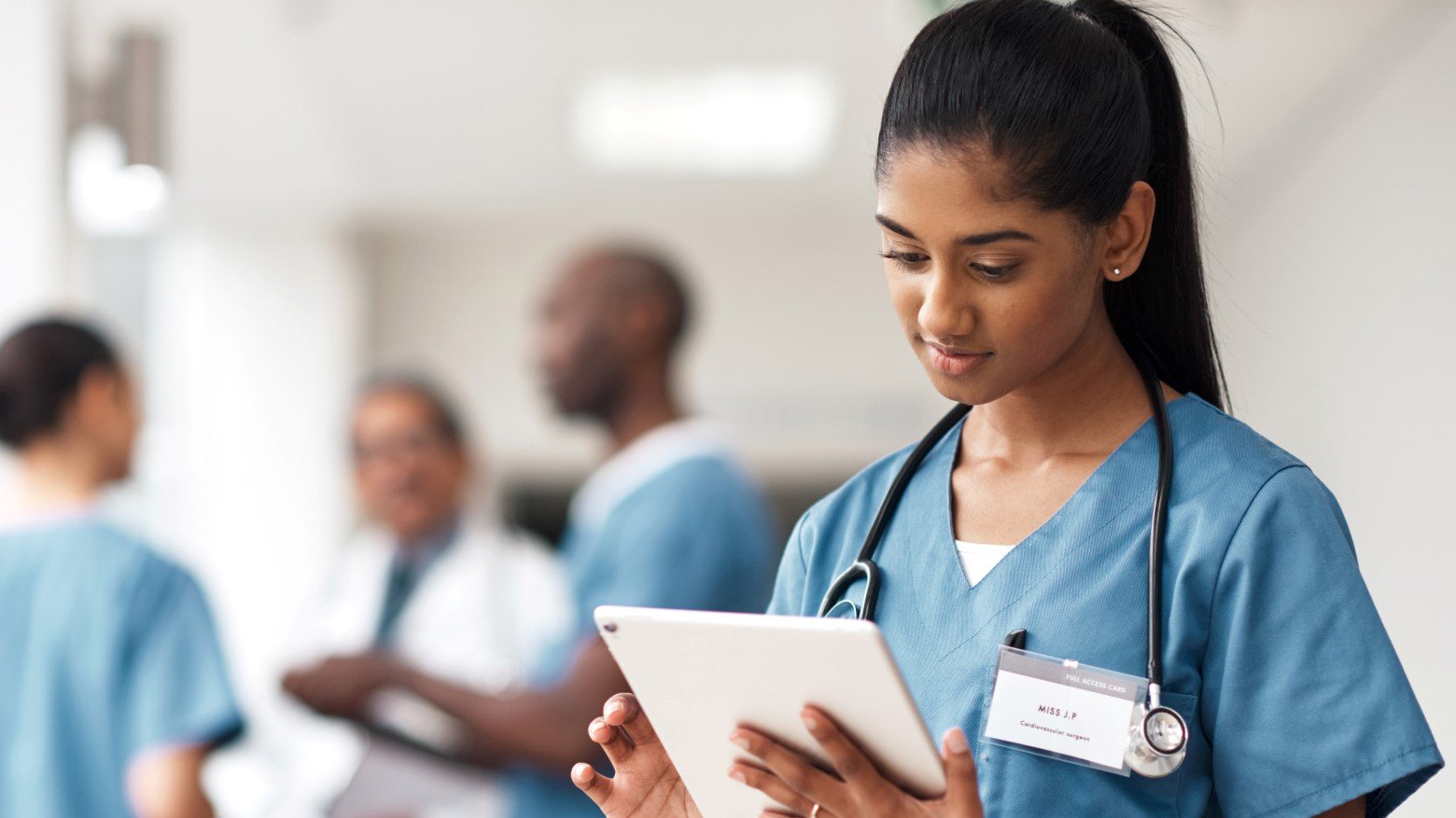 doctor using tablet with other physicians in background
