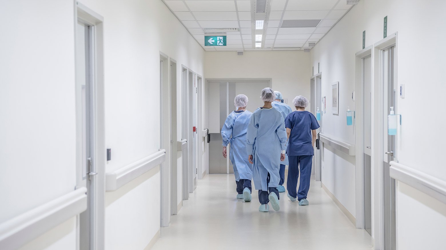  A group of doctors in medical scrubs walk down a hospital hallway