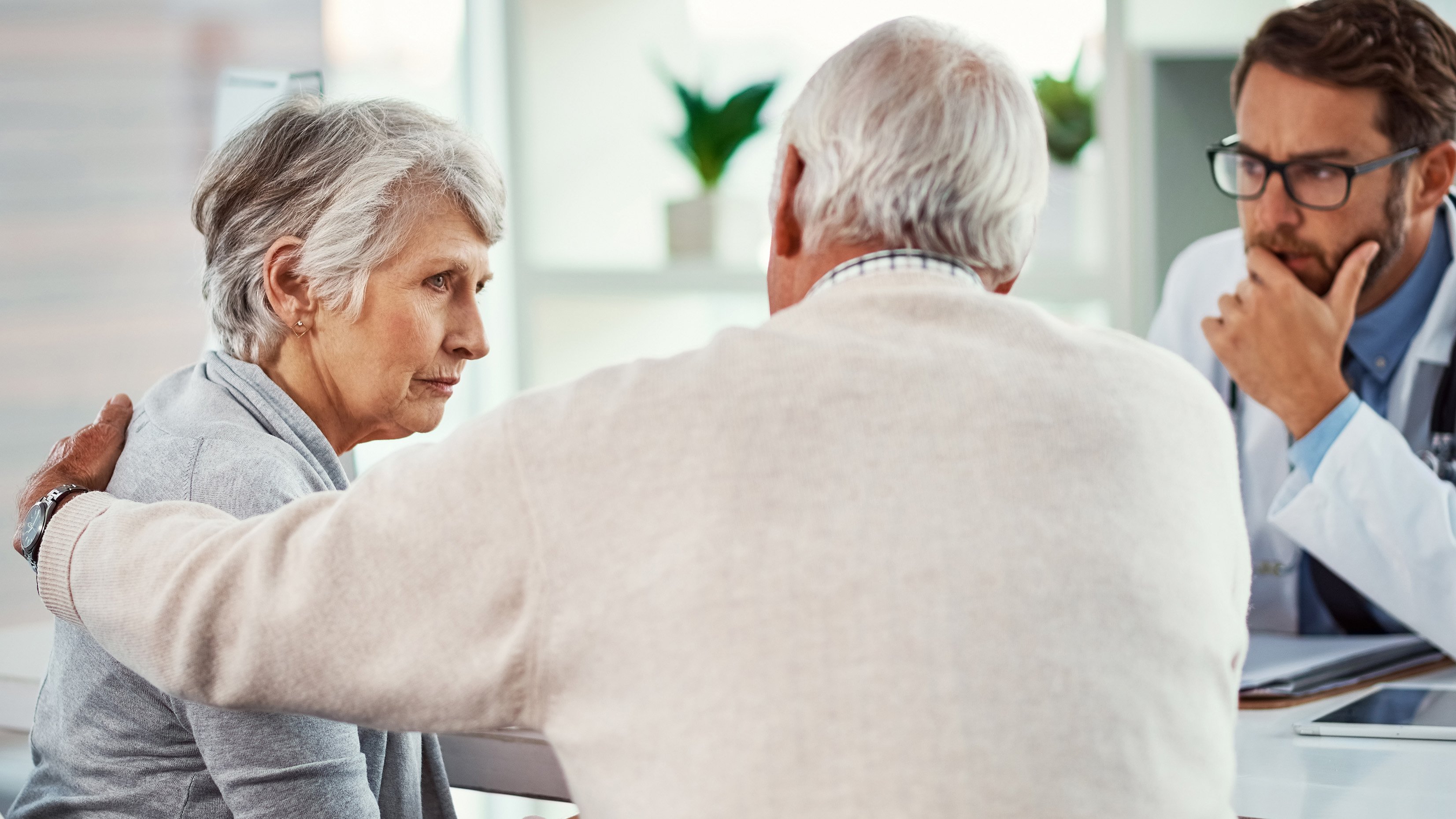 doctor and man comforting older female patient