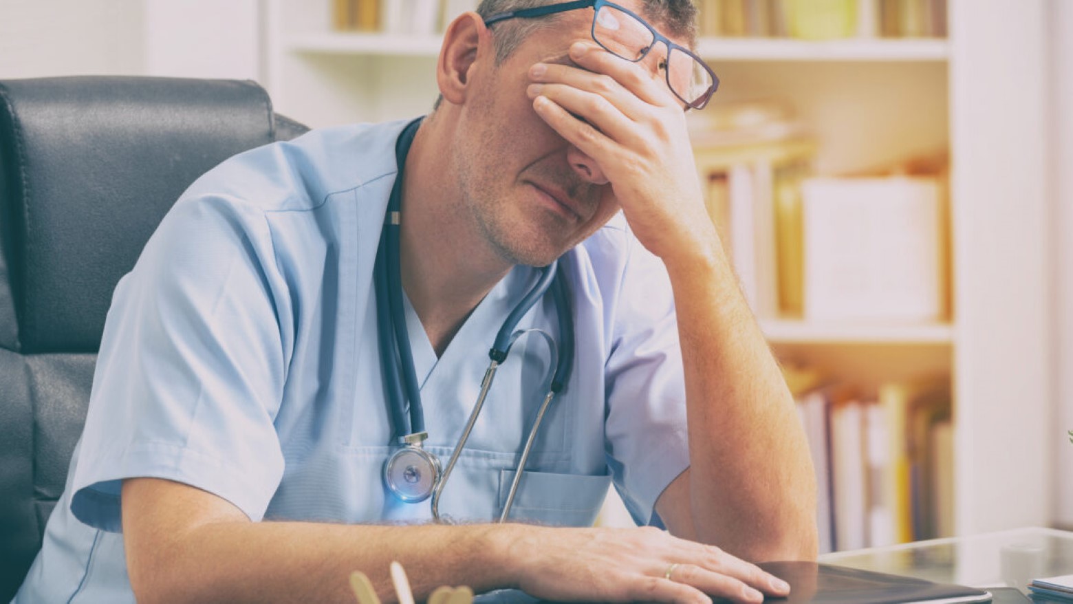 Male doctor with head in hands