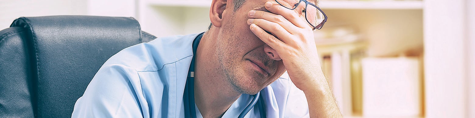 Male doctor with head in hands (4x1).jpg