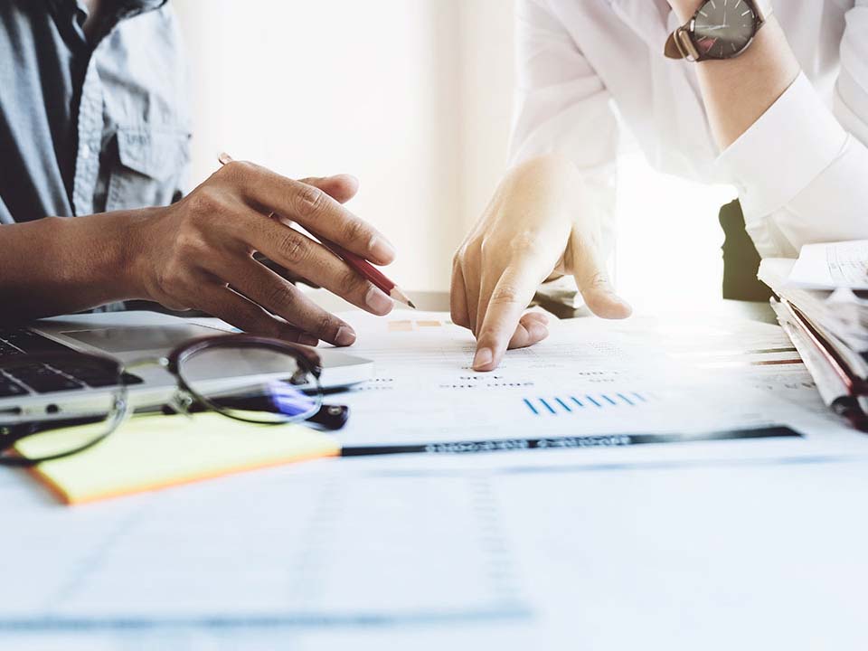 Two people point at charts on paperwork