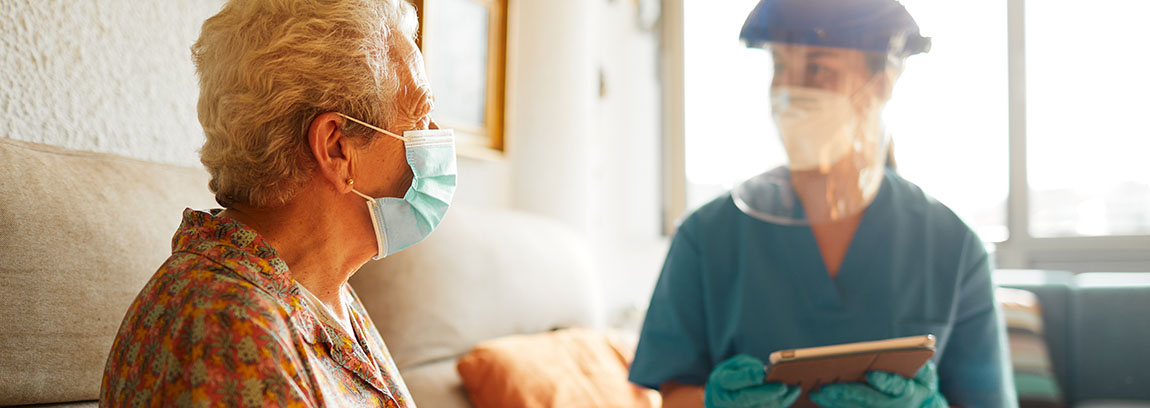 A doctor in full personal protective equipment provides care to an elderly patient
