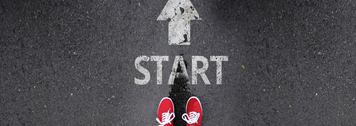 A person stands before a sign on the road that says "start"