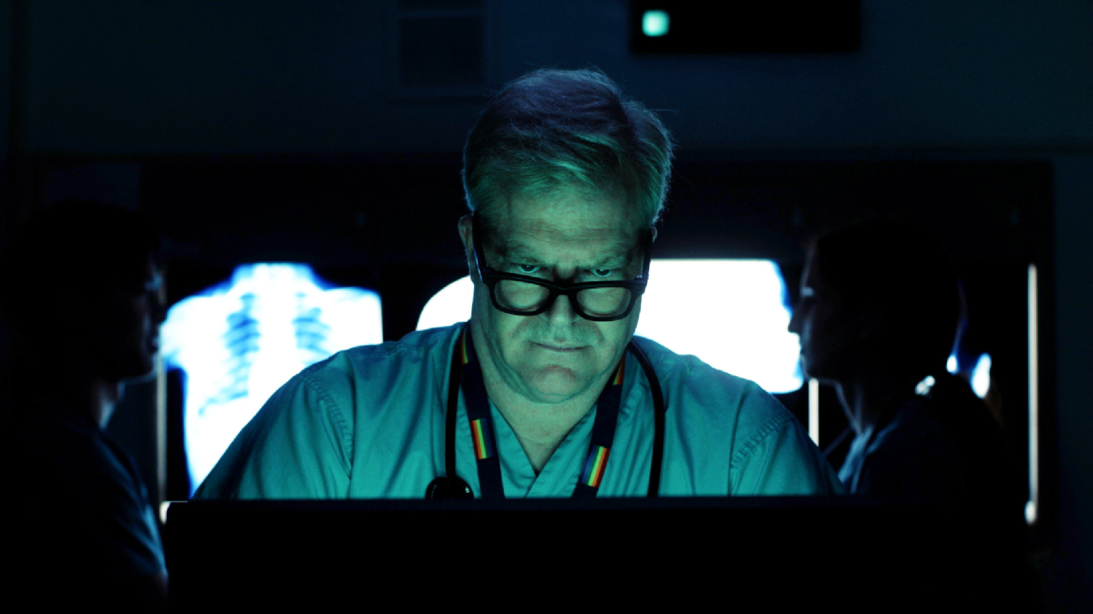 Physician wearing scrubs looking at a screen