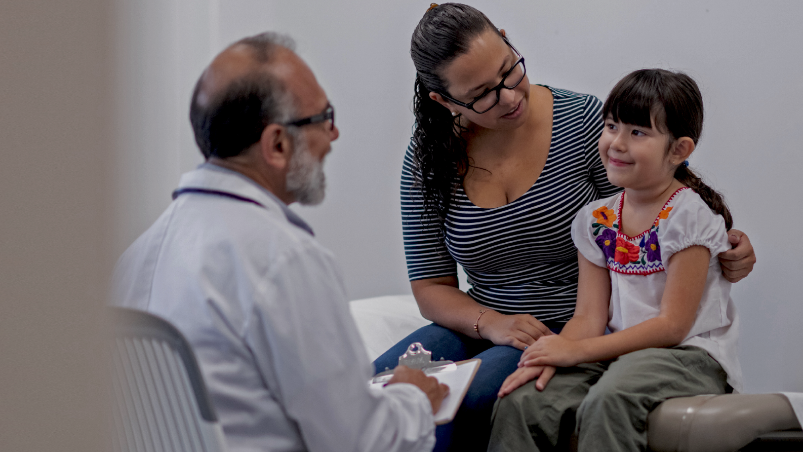A mother and a child speaking with a doctor during a checkup