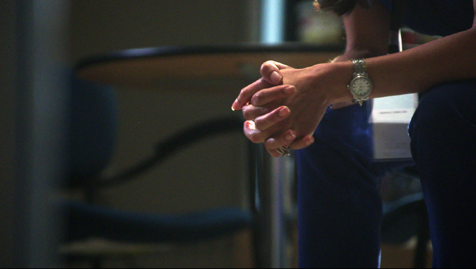 A physician bent over with their hands clasped