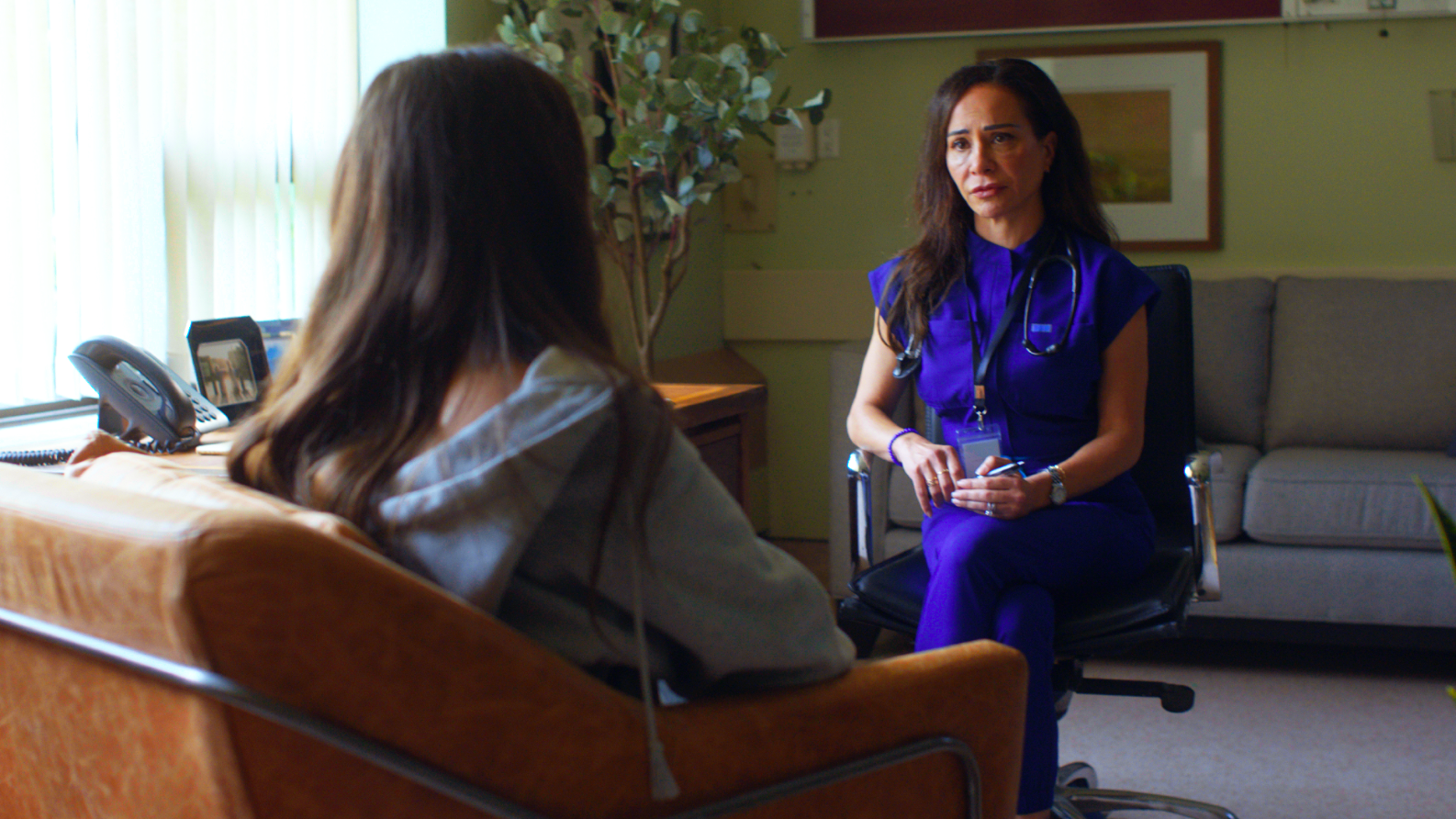A physician sitting down and speaking with a patient