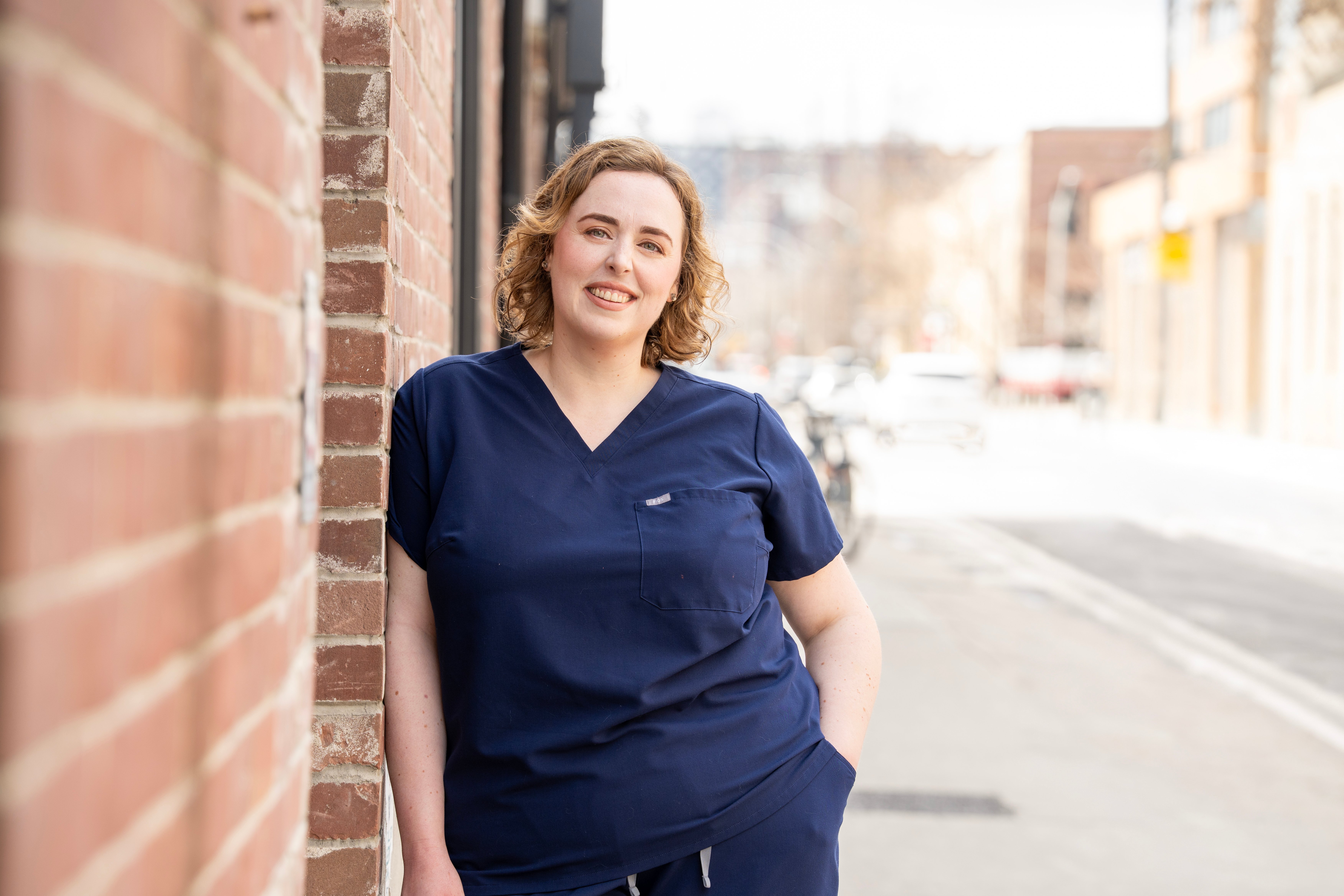 Dr. Rebecca Hicks, a family physician, leaning against a brick wall.