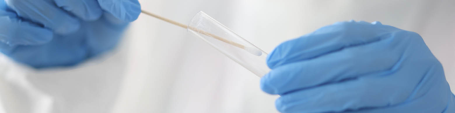 A medical professional places a swab in a test tube.