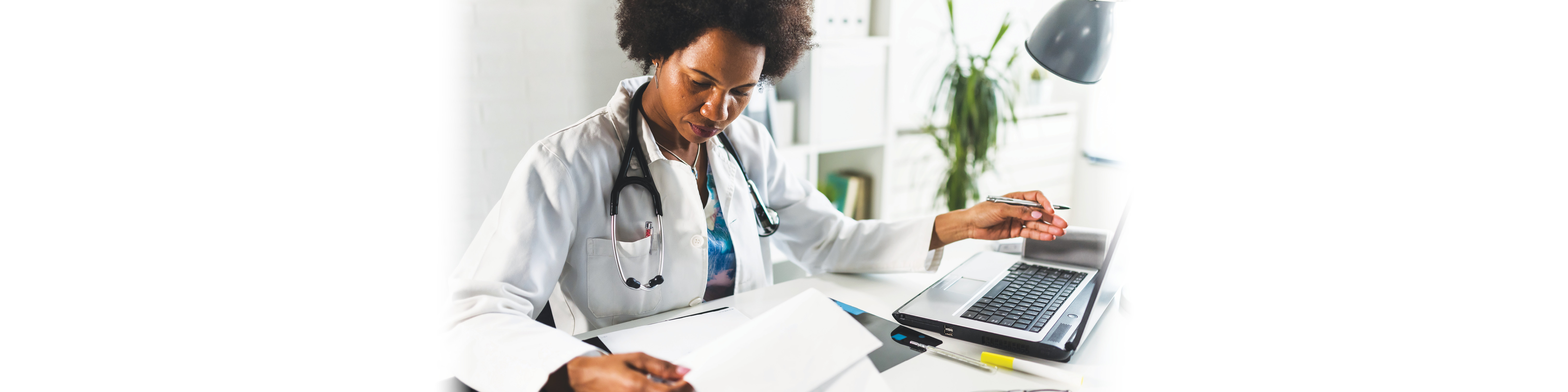 A doctor writes notes at her desk