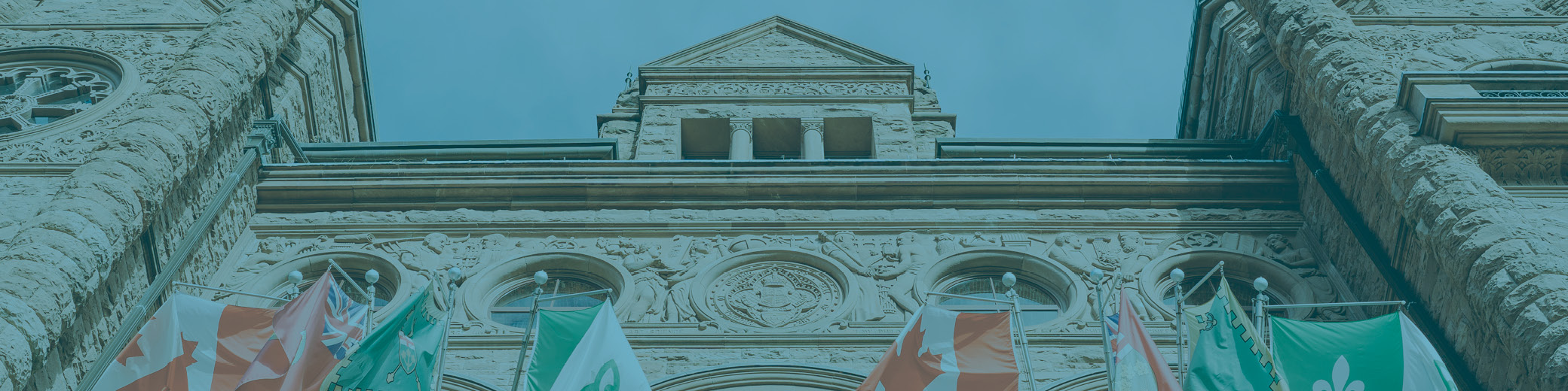 The front facade of the Ontario legislature building at Queen's Park in Toronto is pictured at an angle, looking up.