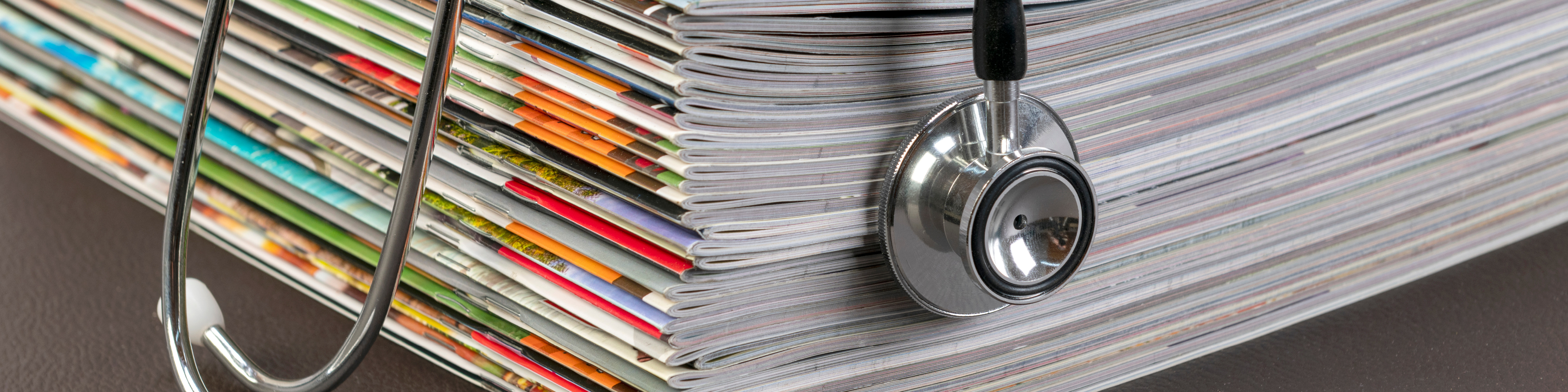 stack of magazines with a stethoscope sitting on top of it